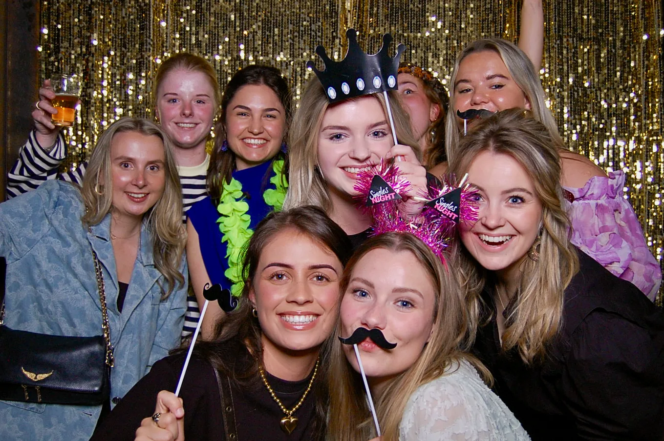Groep vriendinnen poseert met props voor de gouden backdrop